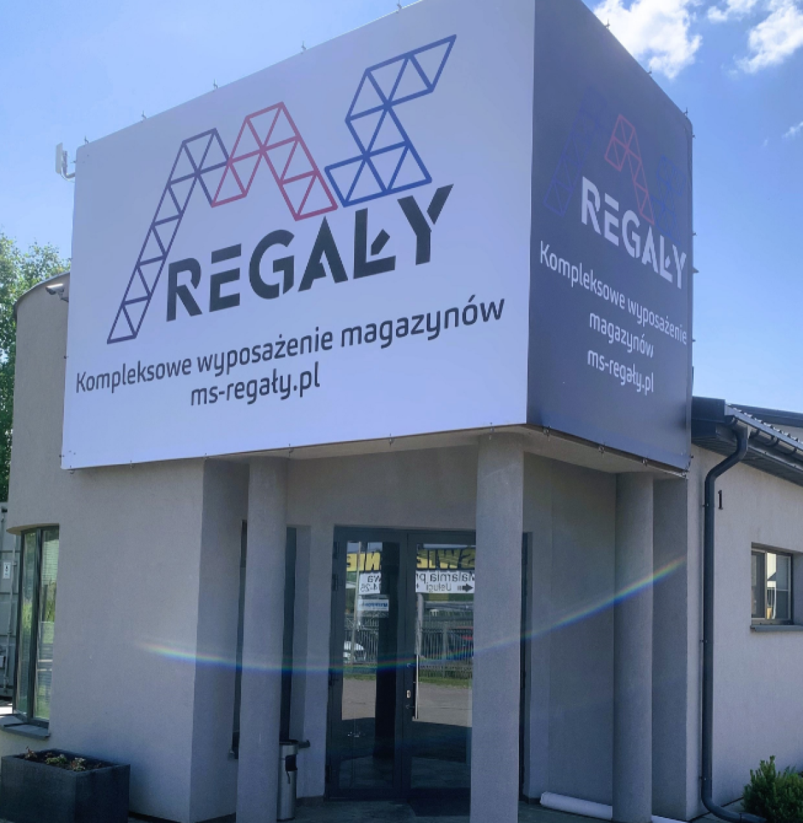 Budynek firmy MS Regały w letnim otoczeniu.