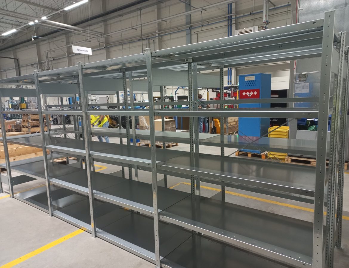 Przemysłowy regał magazynowy z czterema poziomami półek w hali produkcyjnej