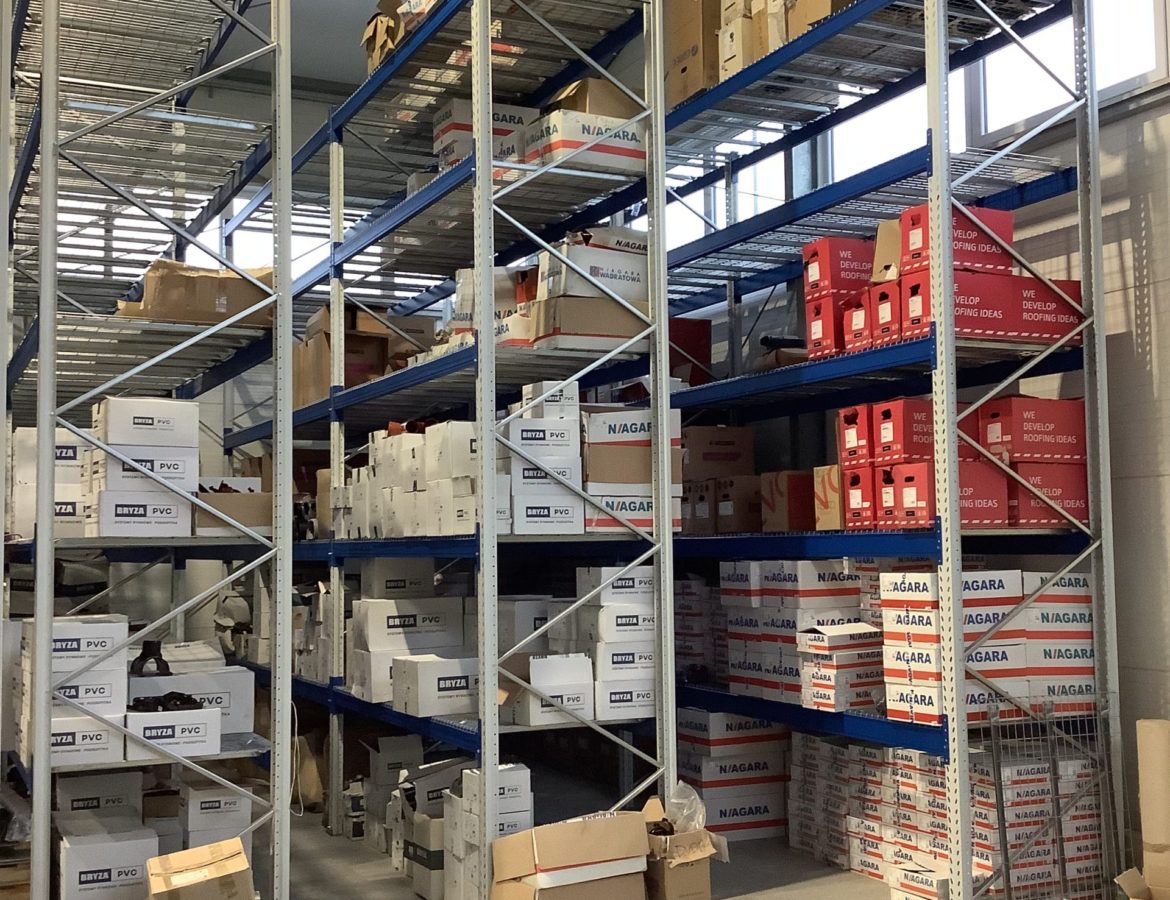 Zapełnione regały magazynowe z produktami PVC i NIAGARA oraz czerwonymi pudełkami