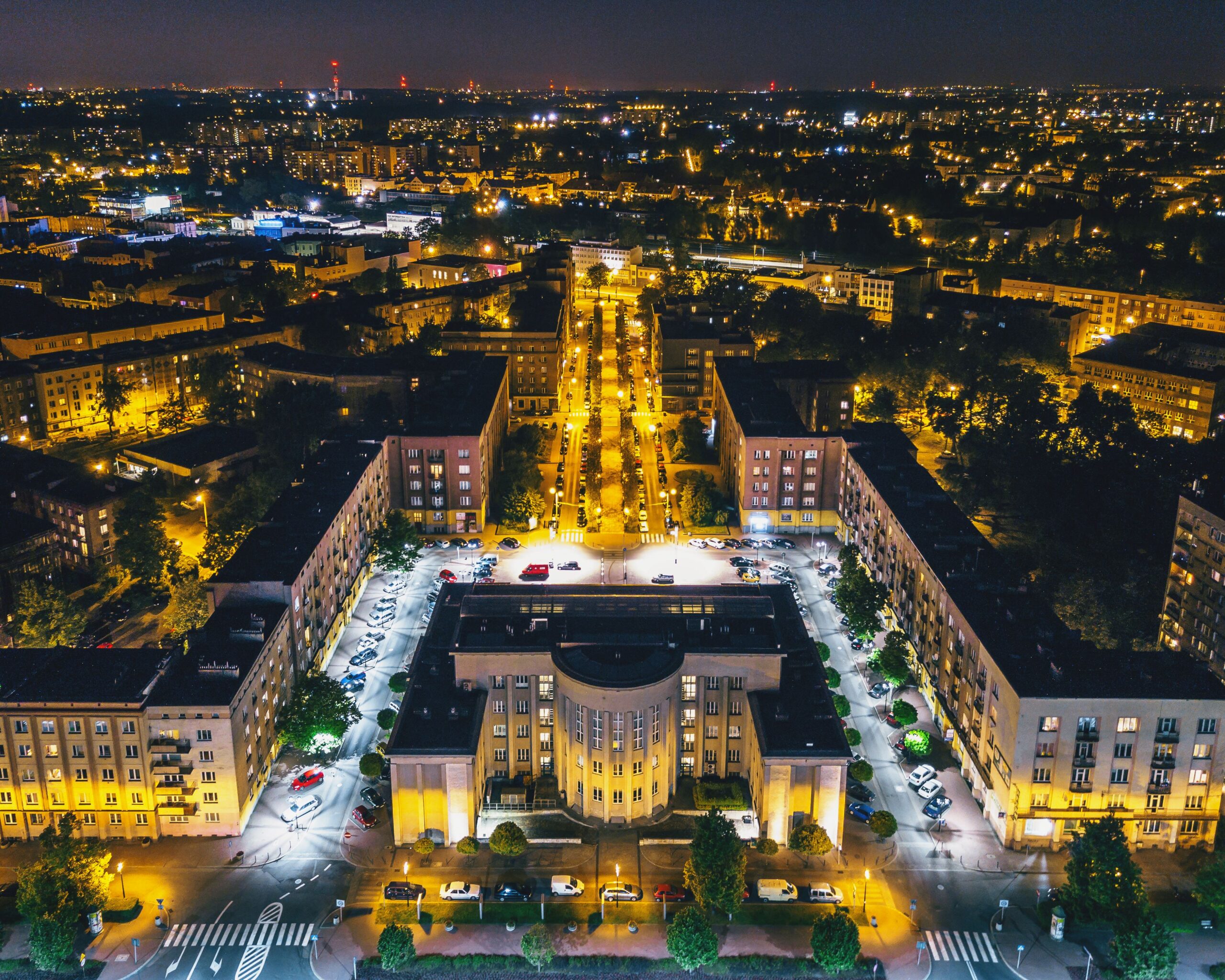 Nocna panorama Sosnowca z lotu ptaka, modernistyczna zabudowa dzielnicy Środula z charakterystycznym półokrągłym budynkiem i oświetlonymi ulicami. Regały Magazynowe w Sosnowcu